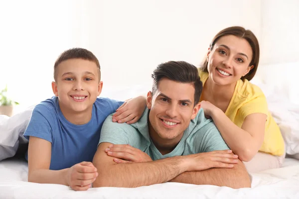 Familia joven feliz juntos en la cama grande — Foto de Stock