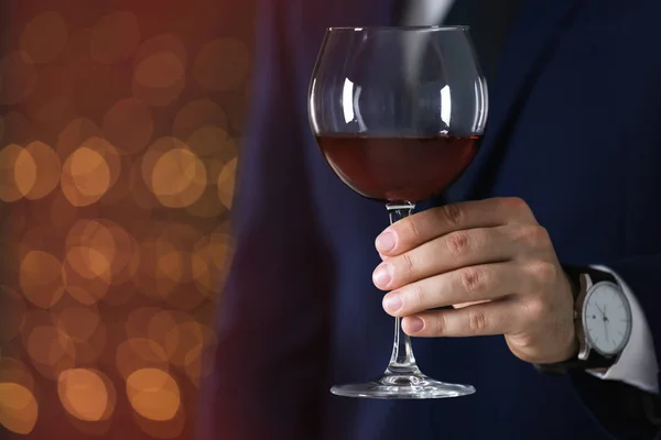 Man i formell kostym med glas vin mot suddig bakgrund, närbild. Utrymme för text — Stockfoto