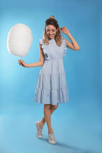 Volledige lengte portret van mooie jonge vrouw met smakelijke suikerspin op blauwe achtergrond — Stockfoto