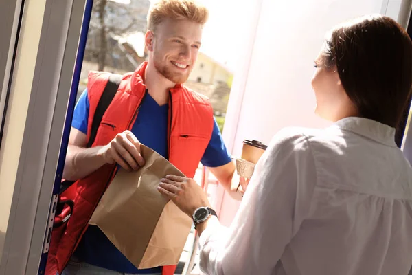 Corriere che dà ordine a giovane donna a porta aperta. Servizio di consegna cibo — Foto Stock