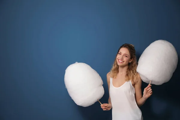 Retrato de mujer joven y bonita con algodón de azúcar sobre fondo azul. Espacio para texto — Foto de Stock