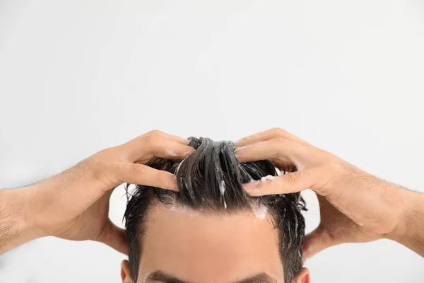 Homem aplicando shampoo em seu cabelo contra fundo claro, close-up. Espaço para texto — Fotografia de Stock