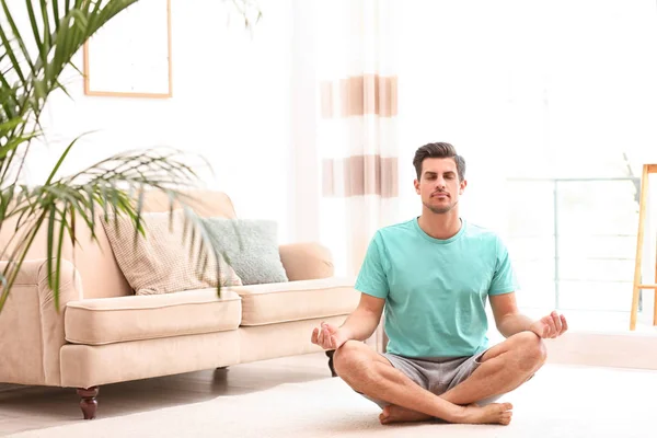 Hombre meditando en el suelo en la sala de estar, espacio para el texto. Concepto zen — Foto de Stock