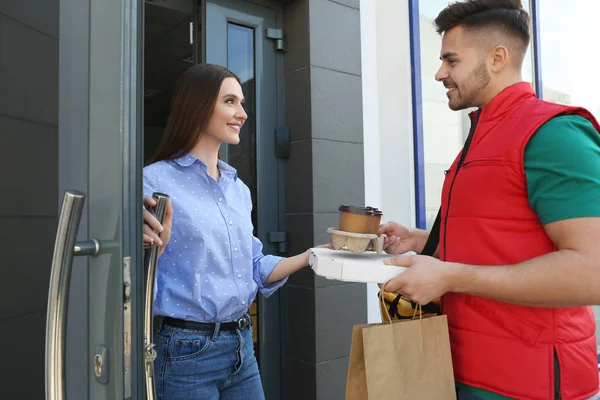 Kurier gibt Befehl an junge Frau an offener Tür. Essenslieferdienst — Stockfoto