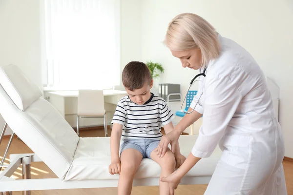 Médecin examinant un petit patient avec un problème de genou en clinique — Photo