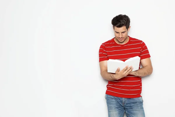 Schöner Mann liest Buch auf weißem Hintergrund, Raum für Text — Stockfoto