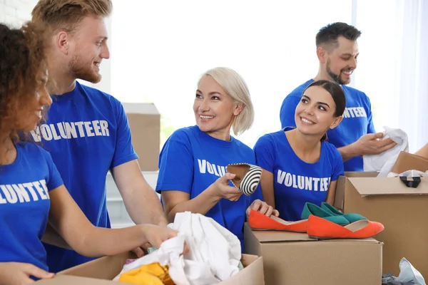 Equipe de voluntários coletando doações em caixas dentro de casa — Fotografia de Stock