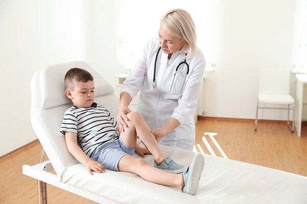 Doctor examining little patient with knee problem in clinic