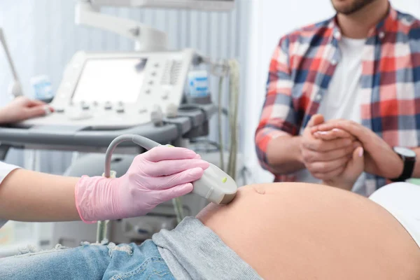 Mann unterstützt seine Frau bei Ultraschalluntersuchung in Klinik, Nahaufnahme — Stockfoto