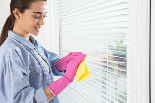 Mooie vrouw schoonmaken raam jaloezieën met Rag binnenshuis, close-up — Stockfoto