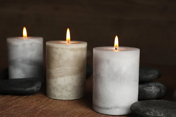 Brennende Kerzen und Wellness-Steine auf Holztisch — Stockfoto