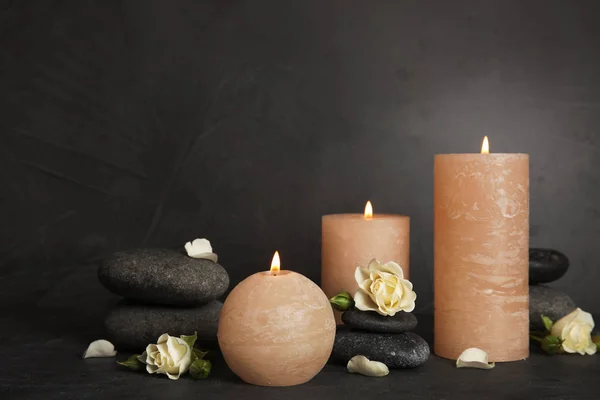 Brennende Kerzen, Wellness-Steine und Blumen auf dunkelgrauem Tisch, Platz für Text — Stockfoto