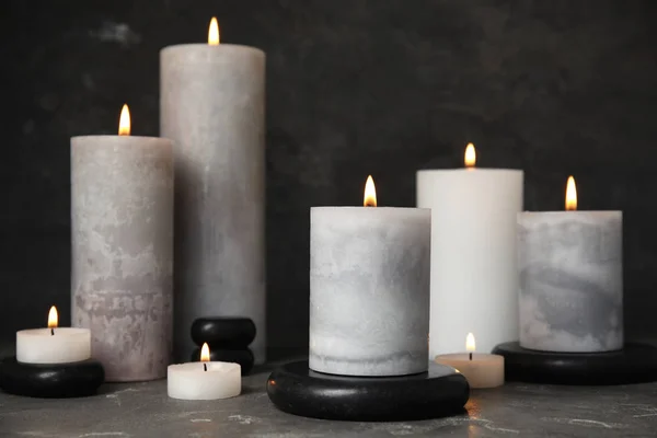 Burning candles and black spa stones on grey table — Stock Photo, Image