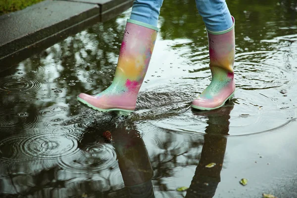 Woman with rubber boots in puddle, closeup. Rainy weather