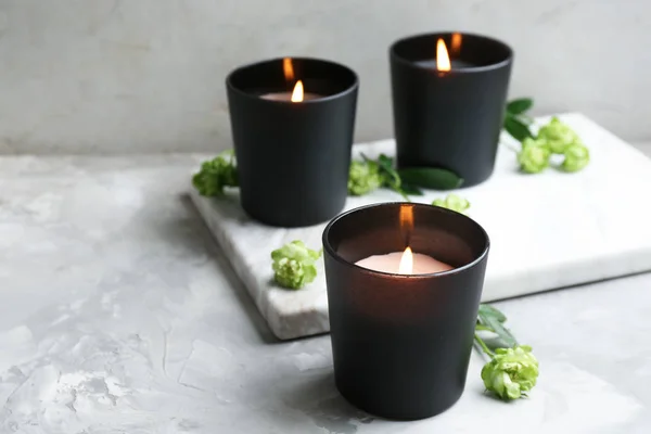 Bränna ljus med blommor på grått bord, utrymme för text — Stockfoto