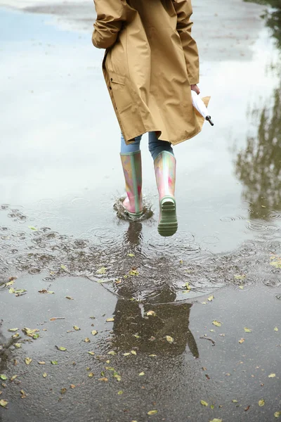 水たまりの中でゴムブーツを履いた女性、クローズアップ。雨天 — ストック写真