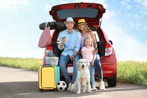 Jeune famille avec bagages et chien près du coffre de la voiture à l'extérieur — Photo