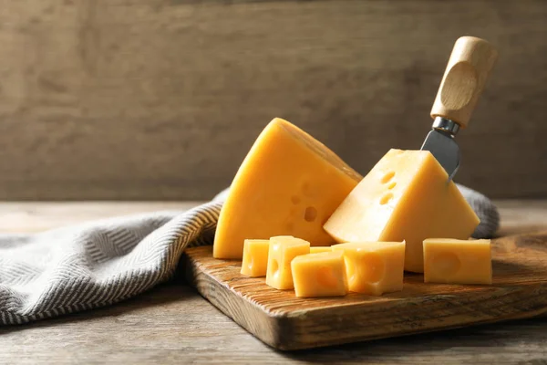 Σανίδα σερβιρίσματος με νόστιμο τυρί στο ξύλινο τραπέζι, Χώρος για κείμενο — Φωτογραφία Αρχείου