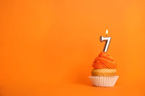 Cupcake d'anniversaire avec numéro sept bougie sur fond orange, espace pour le texte — Photo