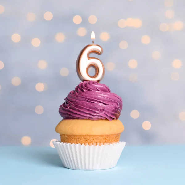 Cupcake d'anniversaire avec numéro six bougie sur la table contre les lumières festives — Photo