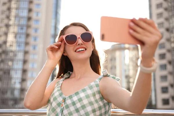 Hermosa joven con gafas de sol tomando selfie al aire libre — Foto de Stock