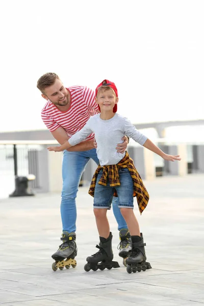 Батько і син катаються на ковзанах на міській вулиці — стокове фото