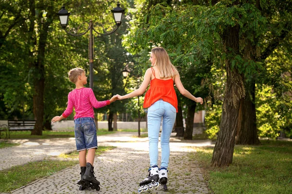 Mother and son roller skating in summer park, back view — Stock Photo, Image