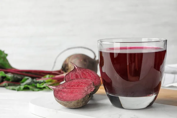 Corte la remolacha y el vaso de jugo en la mesa blanca. Espacio para texto — Foto de Stock