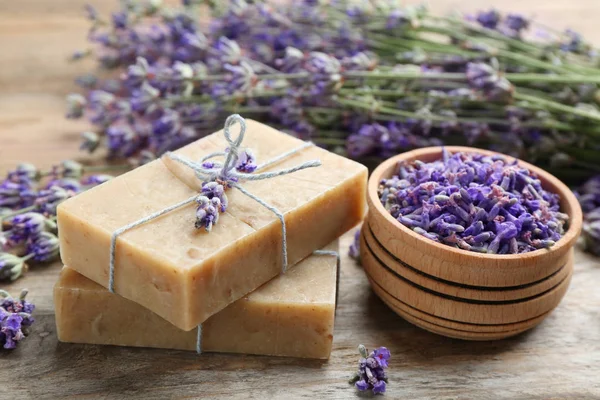 Handmade soap bars with lavender flowers on brown wooden table, closeup — Stock Photo, Image