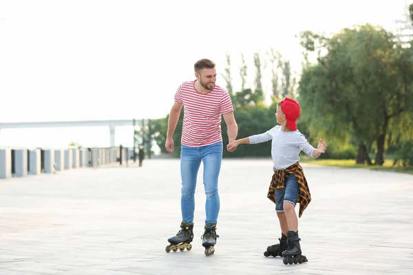 Отец и сын катаются на роликовых коньках по городской улице — стоковое фото