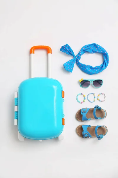Kompozycja z niebieskim walizka i akcesoriami dla dzieci na białym tle, widok z góry. Wakacje — Zdjęcie stockowe