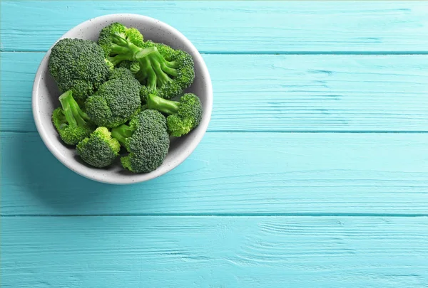 Mangkuk brokoli hijau segar di meja kayu biru, pemandangan atas. Ruang untuk teks — Stok Foto