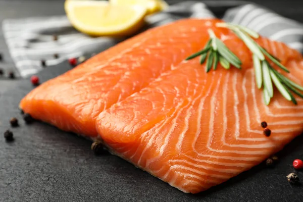 Fresh salmon fillet with rosemary on slate board, closeup