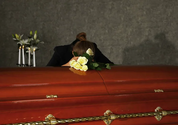 葬儀場で白いバラで棺の近くで悲しむ悲しい女性 — ストック写真
