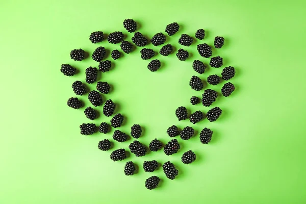 Heart shaped frame made of tasty blackberries on green background, top view with space for text — Stock Photo, Image