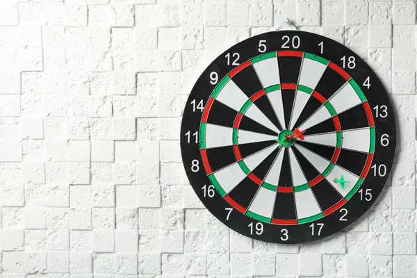 Arrows hitting dart board on white textured wall. Space for text