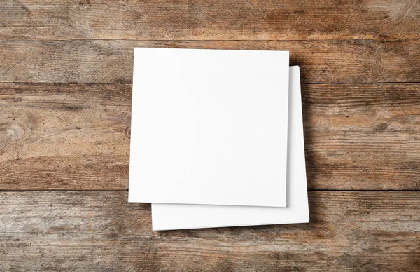 Stos pustych arkuszy papieru do broszury na drewnianym tle, widok z góry. Makiety — Zdjęcie stockowe