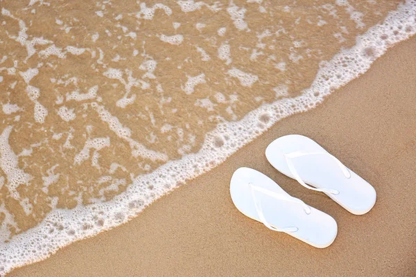 Fehér flip papucs a homok közelében tenger, felülnézet helyet a szöveg. Strandtartozékok — Stock Fotó