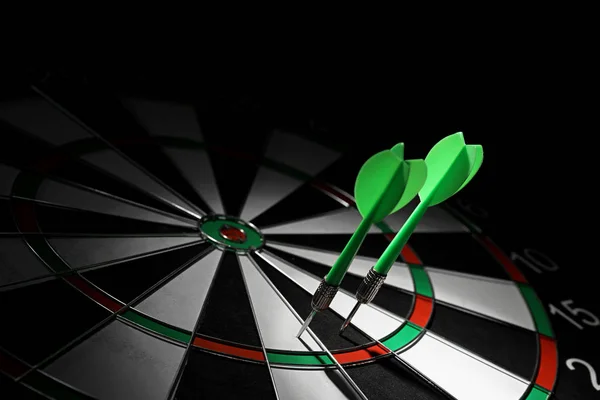 Green arrows hitting dart board against black background. Space for text — Stock Photo, Image