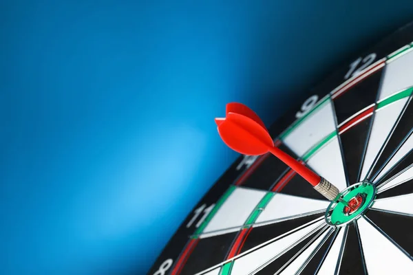 Flecha roja golpeando objetivo en tablero de dardos contra fondo azul. Espacio para texto —  Fotos de Stock