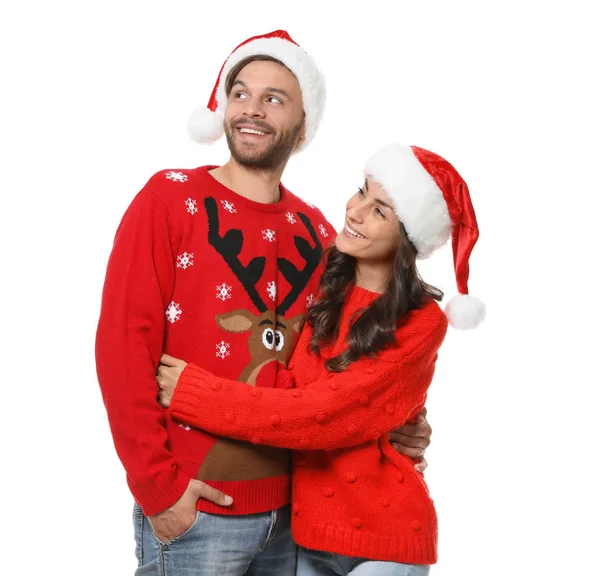 Young couple in Christmas sweaters and hats on white background — Stock Photo, Image