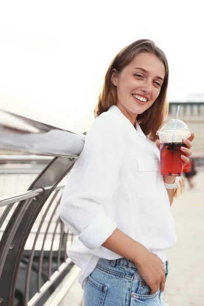在城市街道上喝清凉饮料的年轻女子 — 图库照片