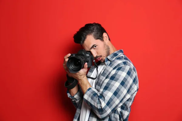 Fotógrafo emocional com câmera profissional em fundo vermelho — Fotografia de Stock