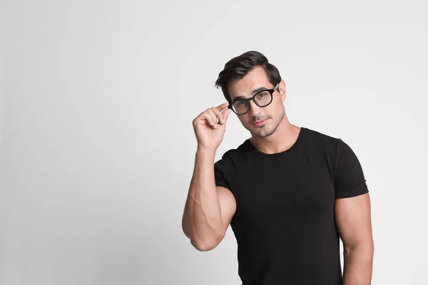 Retrato de jovem bonito em camiseta preta com óculos em fundo cinza. Espaço para texto — Fotografia de Stock