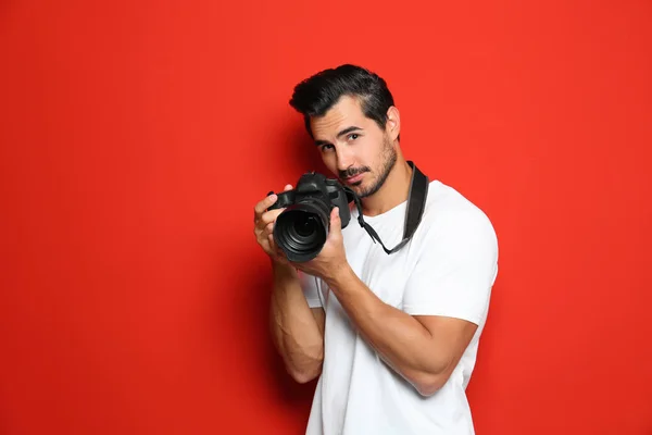 Jovem fotógrafo com câmera profissional em fundo vermelho. Espaço para texto — Fotografia de Stock