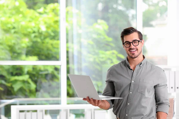 Guapo joven que trabaja con el ordenador portátil en interiores —  Fotos de Stock