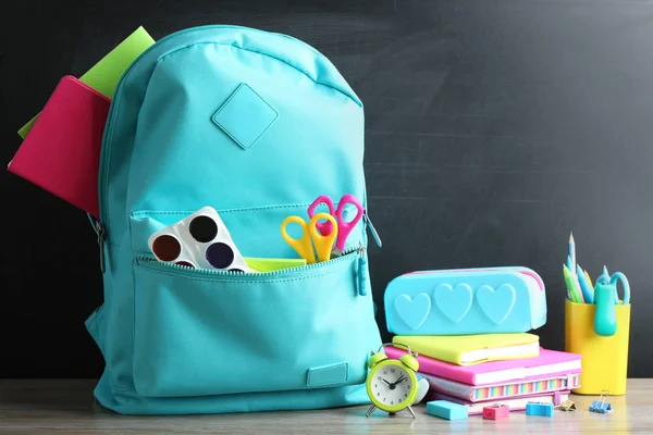 Sırt çantası tebeşir tahtası yakınında masada farklı okul kırtasiye dolu — Stok fotoğraf