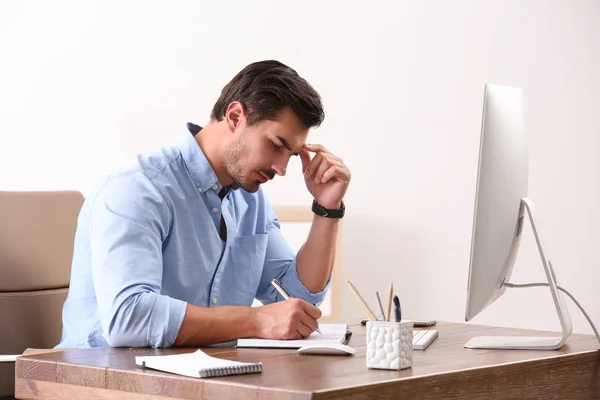 Jovem bonito trabalhando com computador à mesa no escritório — Fotografia de Stock