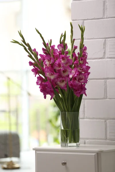 Vas dengan indah bunga gladiolus merah muda di laci dada di kamar — Stok Foto