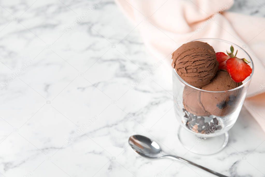 Glass bowl of chocolate ice cream with strawberry served on marble table, space for text